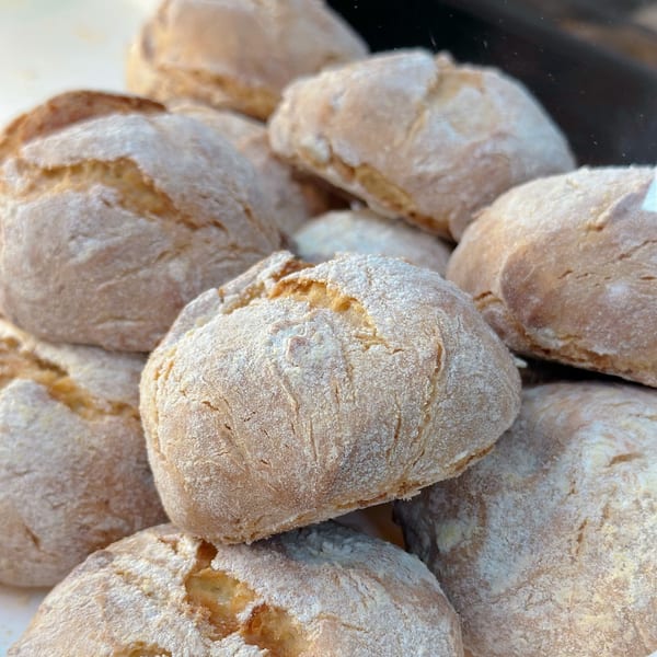 Close-up of several freshly baked, flour-dusted Brazilian cheese breads (Pão de Queijo).